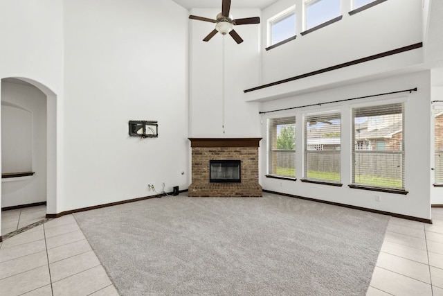 221 Mandana St, Leander, TX 78641 - unfurnished living room with a towering ceiling, light tile patterned flooring, ceiling fan, healthy amount of natural light, and a fireplace