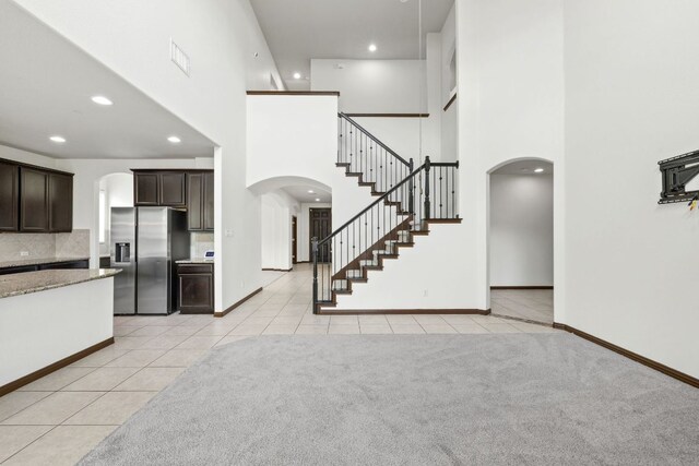 221 Mandana St, Leander, TX 78641 - kitchen with arched walkways, stainless steel fridge, a high ceiling, dark brown cabinets, and light tile patterned flooring