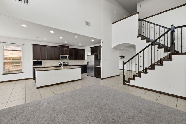 221 Mandana St, Leander, TX 78641 - kitchen with appliances with stainless steel finishes, arched walkways, light tile patterned floors, recessed lighting, and an island with sink