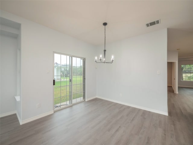 spare room with a chandelier, wood finished floors, and baseboards