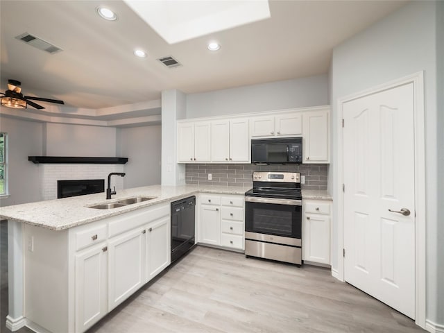 kitchen featuring black appliances, a sink, a peninsula, white cabinets, and tasteful backsplash