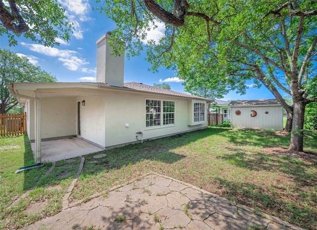 rear view of property with a patio area, a chimney, an outbuilding, stucco siding, and a storage shed