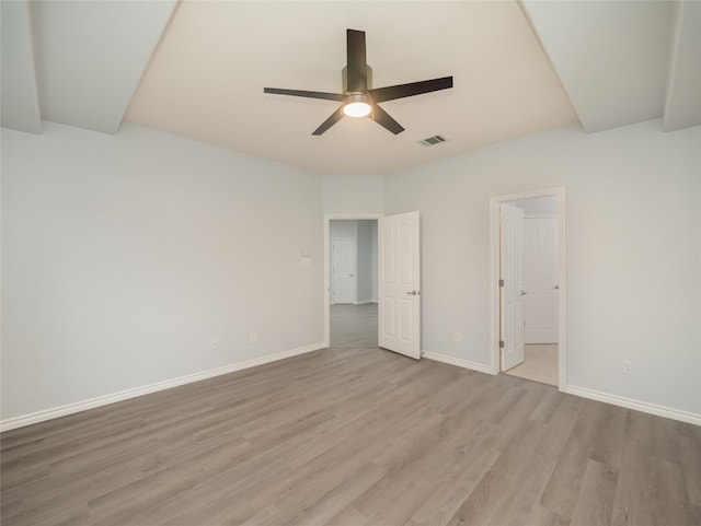 unfurnished bedroom featuring wood finished floors, baseboards, ensuite bathroom, and a ceiling fan