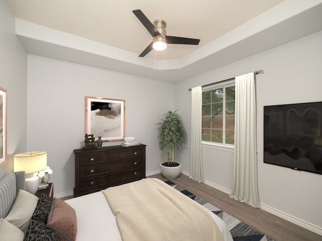bedroom with wood finished floors, baseboards, a ceiling fan, and a raised ceiling