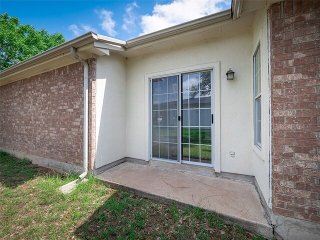 property entrance with brick siding and stucco siding