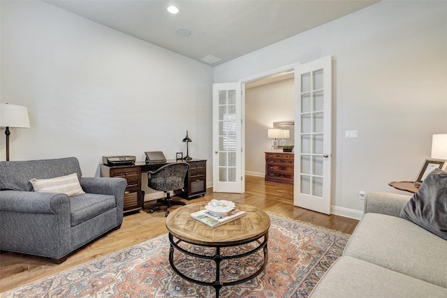 living area featuring french doors, lofted ceiling, wood finished floors, an office area, and baseboards