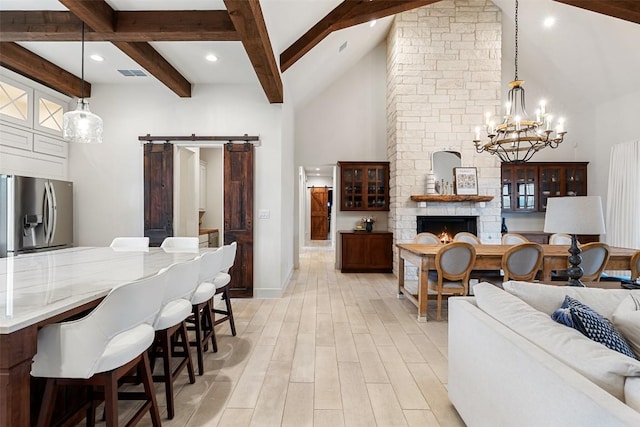1278 Sanctuary Ln, Blanco, TX 78606 - living area with a barn door, beam ceiling, a chandelier, a towering ceiling, and light wood-style floors