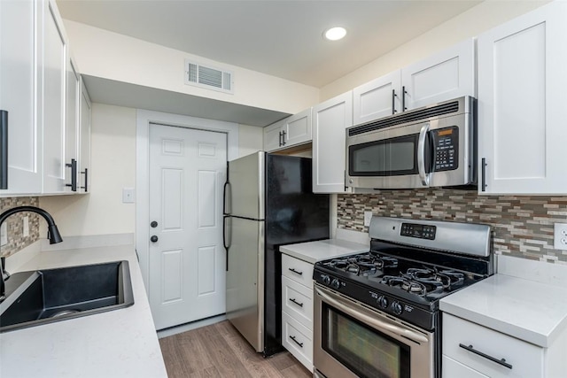 2105 Emerald Isle Dr, Leander, TX 78641 - kitchen featuring appliances with stainless steel finishes, a sink, white cabinets, light countertops, and decorative backsplash