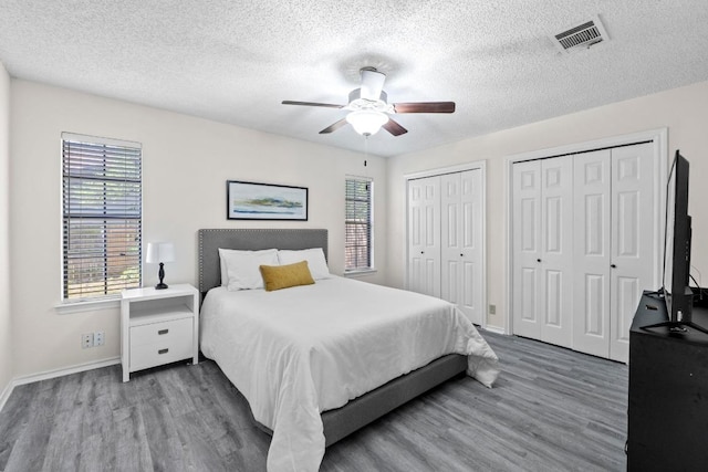 8805 Clearbrook Trl Unit A, Austin, TX 78729 - bedroom featuring wood finished floors, multiple closets, multiple windows, a textured ceiling, and ceiling fan