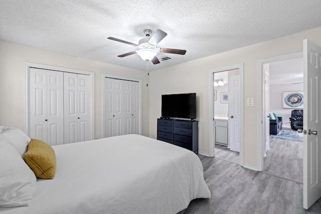 8805 Clearbrook Trl Unit A, Austin, TX 78729 - bedroom featuring wood finished floors, a textured ceiling, multiple closets, a ceiling fan, and baseboards