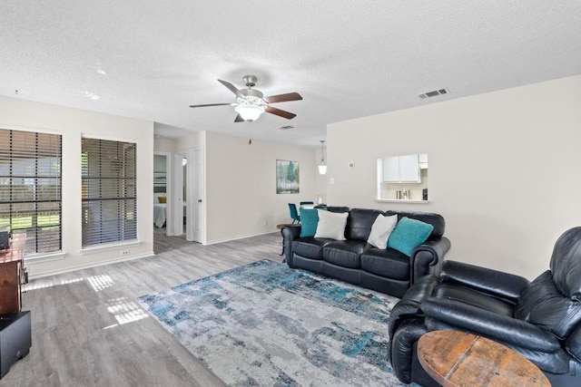 8805 Clearbrook Trl Unit A, Austin, TX 78729 - living room featuring wood finished floors, a ceiling fan, a textured ceiling, and baseboards