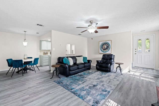 8805 Clearbrook Trl Unit A, Austin, TX 78729 - living room featuring a textured ceiling, light wood-type flooring, baseboards, and ceiling fan