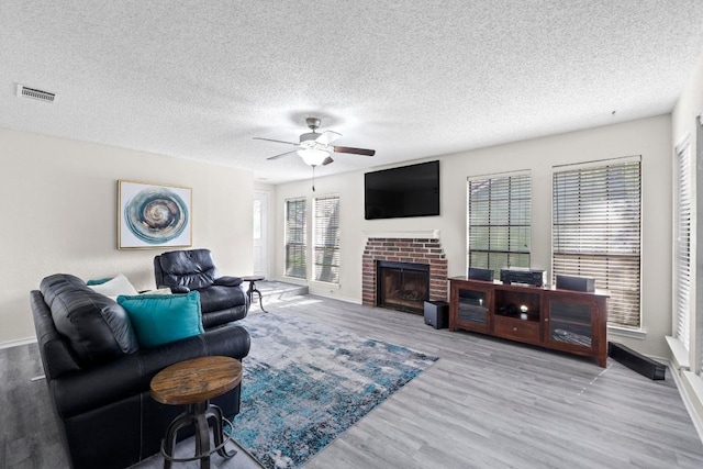 8805 Clearbrook Trl Unit A, Austin, TX 78729 - living room featuring wood finished floors, a ceiling fan, a fireplace, a textured ceiling, and baseboards