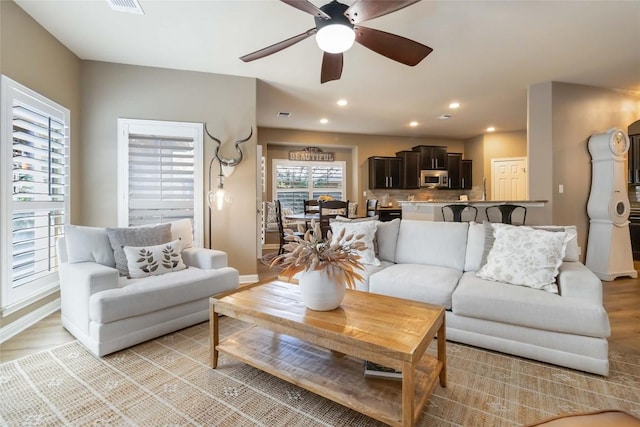 living area featuring a ceiling fan, recessed lighting, light wood-style flooring, and baseboards