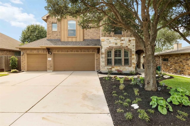 view of front of home featuring concrete driveway, an attached garage, fence, stone siding, and brick siding