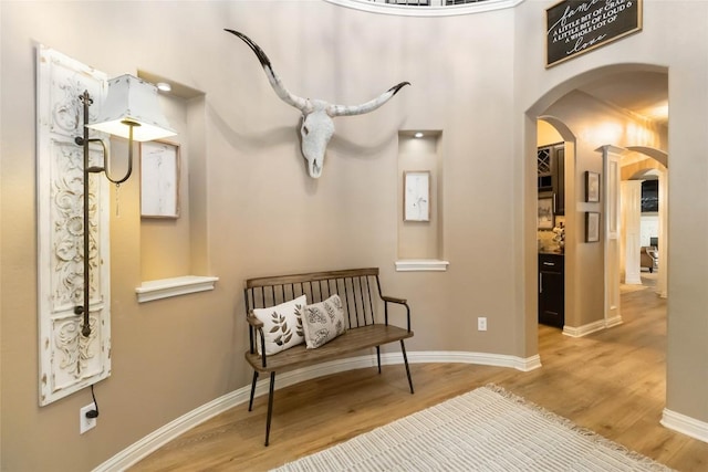 living area featuring arched walkways, wood finished floors, and baseboards