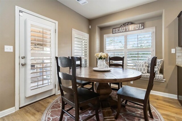 dining space with light wood-style flooring and baseboards