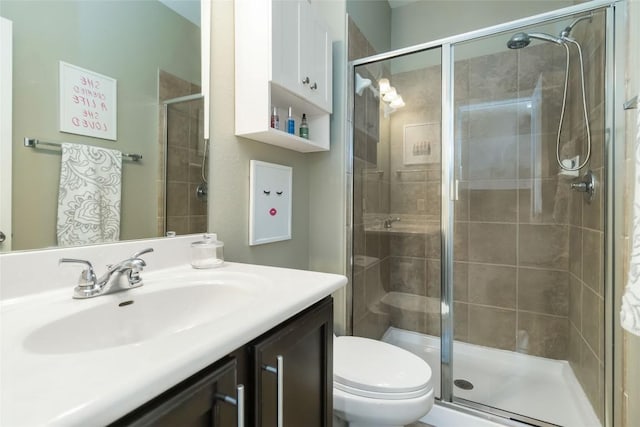 bathroom with a stall shower, vanity, and toilet