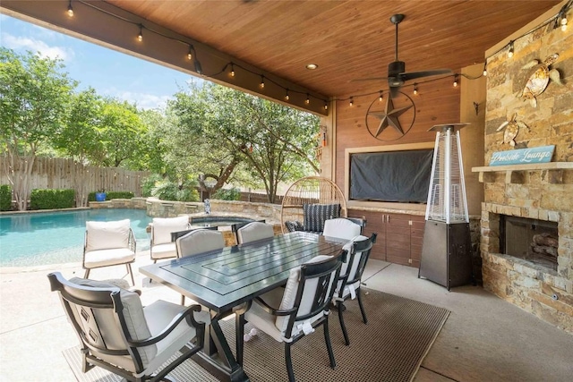 view of patio featuring an outdoor stone fireplace, a fenced backyard, a ceiling fan, and outdoor dining area
