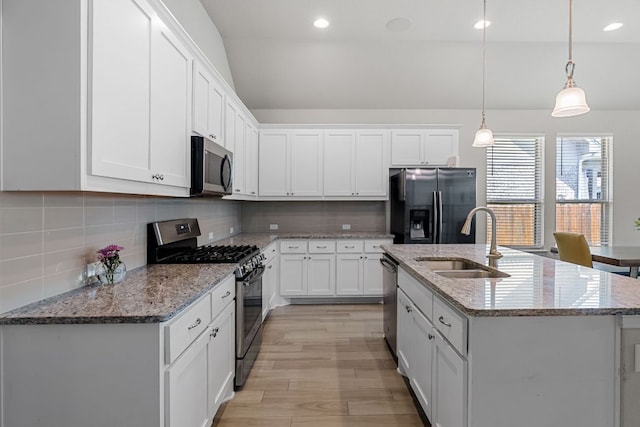 12709 Twisted Root Dr, Manchaca, TX 78652 - kitchen featuring appliances with stainless steel finishes, a sink, lofted ceiling, light wood-style flooring, and backsplash