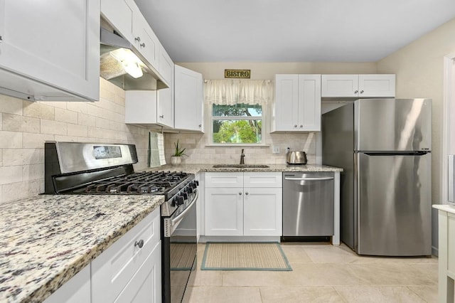 kitchen featuring appliances with stainless steel finishes, under cabinet range hood, a sink, and white cabinetry