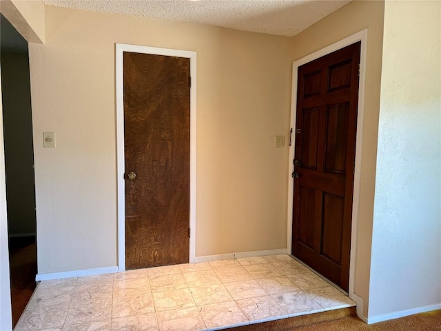 foyer with baseboards and a textured ceiling