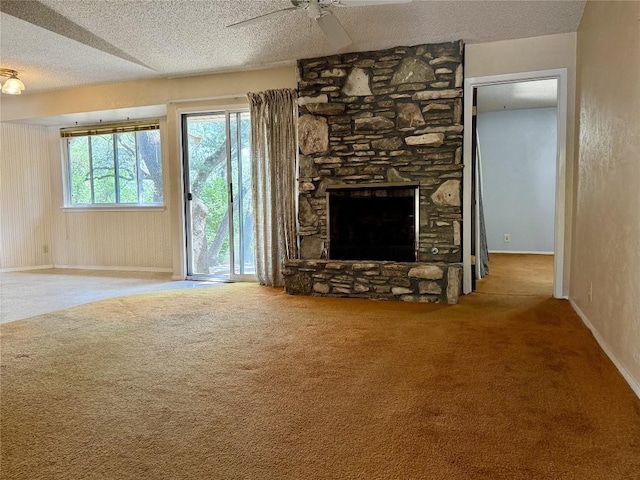 unfurnished living room with carpet flooring, ceiling fan, a textured ceiling, baseboards, and a fireplace