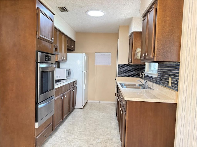 kitchen featuring white appliances, a sink, a warming drawer, light countertops, and baseboards