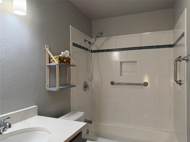 full bath featuring a textured wall, toilet, vanity, and  shower combination