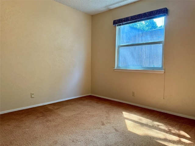 carpeted empty room featuring a textured ceiling and baseboards