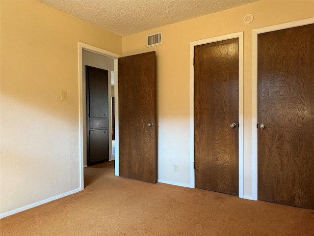 unfurnished bedroom featuring carpet, baseboards, and a textured ceiling