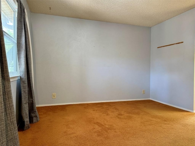 empty room with carpet floors, a textured ceiling, and baseboards