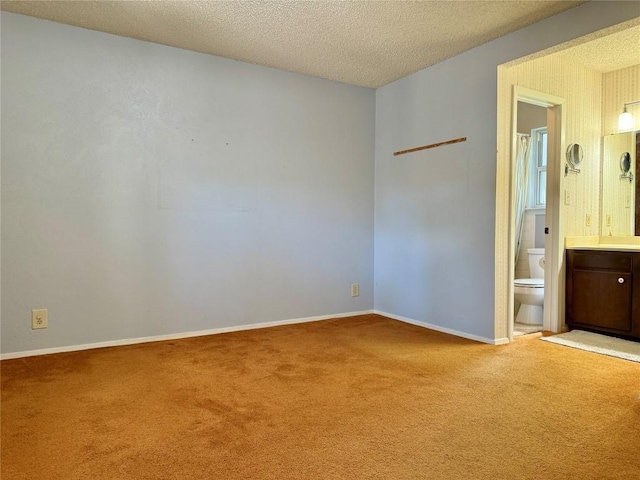 carpeted spare room featuring a textured ceiling and baseboards