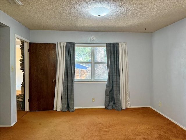 empty room with carpet flooring, a textured ceiling, and baseboards
