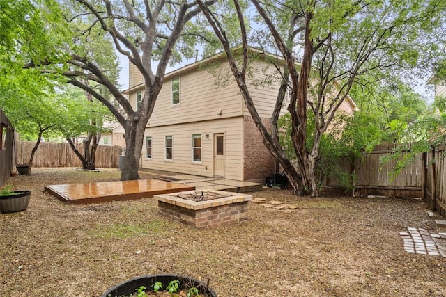 rear view of property featuring a fenced backyard, a wooden deck, and brick siding