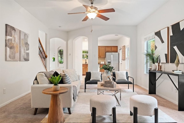 living room with arched walkways, light colored carpet, healthy amount of natural light, and baseboards