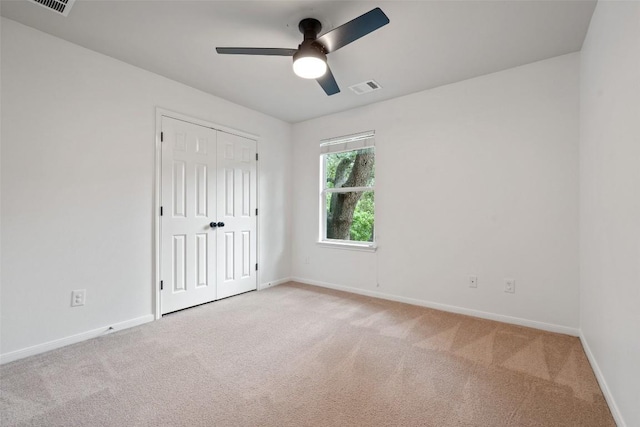 unfurnished bedroom featuring light colored carpet, baseboards, a closet, and ceiling fan