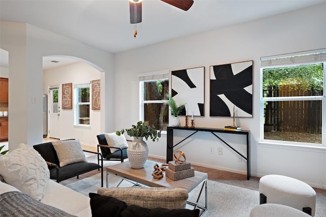 living room featuring arched walkways, plenty of natural light, light carpet, and ceiling fan