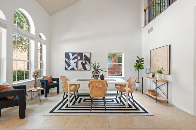 dining room with a high ceiling, light tile patterned floors, and baseboards