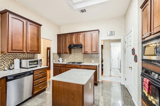 kitchen featuring stainless steel appliances, under cabinet range hood, decorative backsplash, and a kitchen island