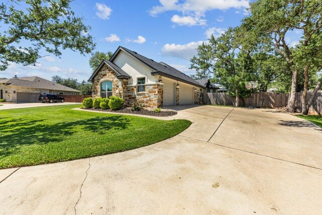 view of front of home featuring stone siding, an attached garage, stucco siding, and concrete driveway