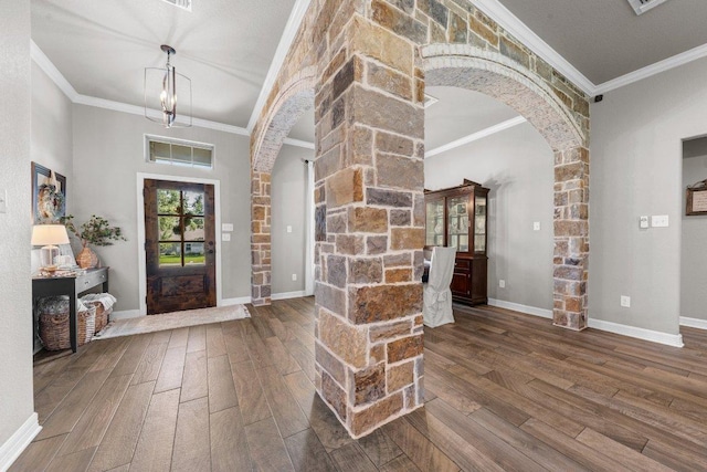 foyer featuring arched walkways, wood finished floors, ornamental molding, and baseboards