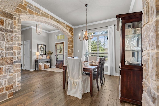 dining area featuring arched walkways, a chandelier, crown molding, wood-type flooring, and baseboards