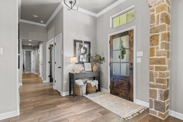 foyer with crown molding, wood finished floors, baseboards, and a towering ceiling