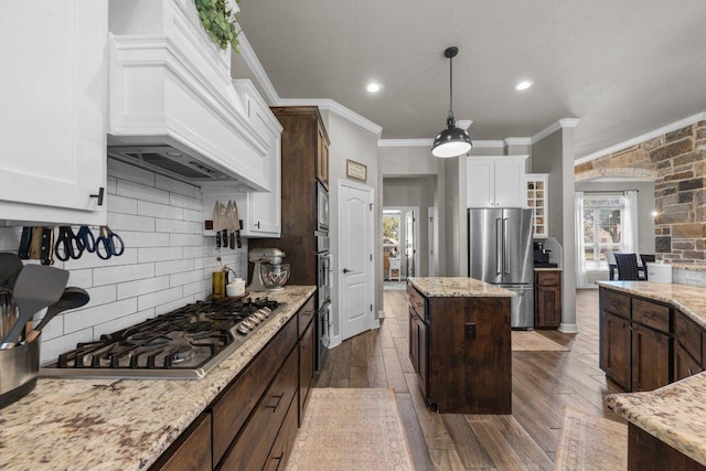 kitchen with appliances with stainless steel finishes, ornamental molding, white cabinets, dark wood-type flooring, and custom exhaust hood