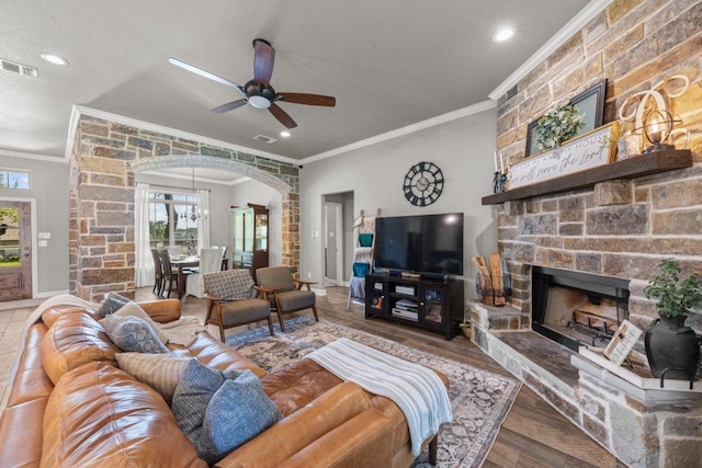 living room featuring ornamental molding, arched walkways, healthy amount of natural light, ceiling fan, and a fireplace