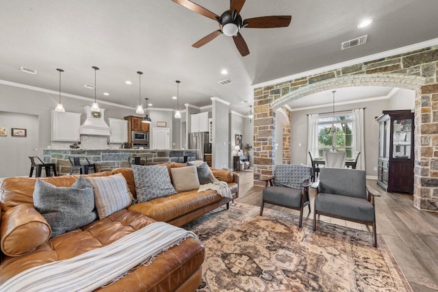 living area with arched walkways, crown molding, a ceiling fan, light wood-style floors, and recessed lighting