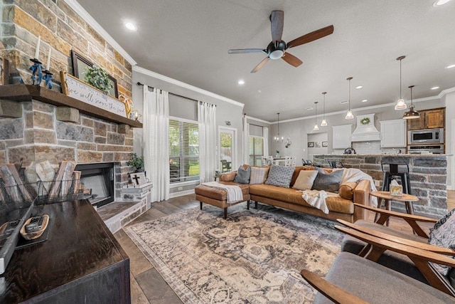 living area featuring crown molding, ceiling fan, a stone fireplace, and recessed lighting