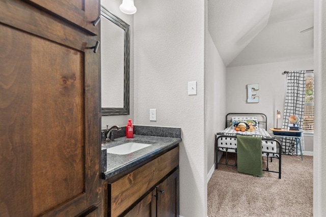 bathroom featuring lofted ceiling, baseboards, vanity, and a textured wall