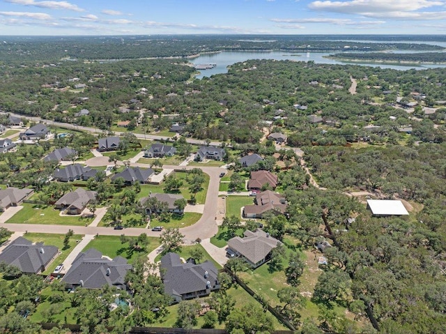 aerial view of property and surrounding area with a large body of water, nearby suburban area, and a heavily wooded area